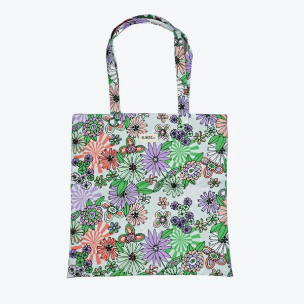 Le sac tote bag est de format carré, avec des anses, il est de couleur vert pâle en fond avec des motifs floraux violet, mauve, saumon, pêche avec des motifs fleuris lui donnant un petit côté vintage année 70. Le tissu est imperméable impression en Europe, et dessiné en France par une illustratrice basée en France Stéphanie Piogé