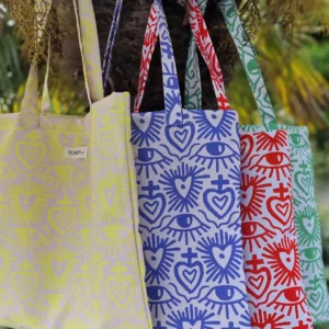 Tote bag carrée ou sac banane XL avec des motifs coeurs ex-voto avec une multitude de couleurs, jaune fluo, rouge vif, vert fashy ou vert pelouse ou mauve lilas. Le tissu est imperméable impression en Europe, et dessiné en France par une illustratrice basée en France Stéphanie Piogé Il est assemblé, fabriqué dans un atelier d'insertion en Charente près d'Angoulême à Confolens, le CEDIF, un acteur local de l'économie Charentaise.