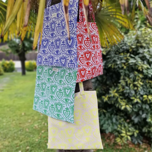 Tote bag carrée ou sac banane XL avec des motifs coeurs ex-voto avec une multitude de couleurs, jaune fluo, rouge vif, vert fashy ou vert pelouse ou mauve lilas. Le tissu est imperméable impression en Europe, et dessiné en France par une illustratrice basée en France Stéphanie Piogé Il est assemblé, fabriqué dans un atelier d'insertion en Charente près d'Angoulême à Confolens, le CEDIF, un acteur local de l'économie Charentaise.