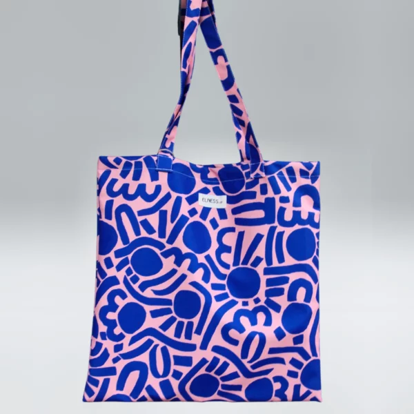 Le sac tote bag est de format carré, avec des anses ou le sac banane XL, il est de couleur bleu klein et saumon avec des motifs abstrait. Le tissu est imperméable impression en Europe, et dessiné en France par une illustratrice basée en France Stéphanie Piogé Il est assemblé, fabriqué dans un atelier d'insertion en Charente près d'Angoulême à Confolens, le CEDIF, un acteur local de l'économie Charentaise.