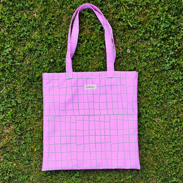 Le sac tote bag est de format carré, avec des anses ou le sac banane XL, il est à carreaux avec des lignes vertes et fond rose bonbon, le cadeau idéal pour la rentrée ou noêl . Le tissu est imperméable impression en Europe, et dessiné en France par une illustratrice basée en France Stéphanie Piogé Il est assemblé, fabriqué dans un atelier d'insertion en Charente près d'Angoulême à Confolens, le CEDIF, un acteur local de l'économie Charentaise. le tissu est imperméable