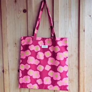 Le grand sac shopping, idéal pour aller en cours au travail, en shopping. Le sac est en coton épais, le fonds est terracotta-rose avec un motif fleuri abstrait rose poudré et son centre ocre doré, une poche intérieur dans le même motif. Il est fabriqué en France la fabrication est locale en Charente dans un atelier d'insertion