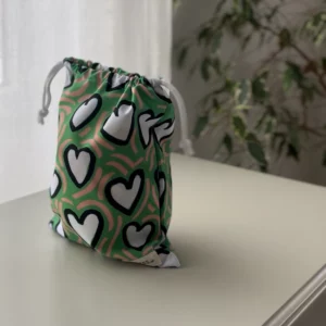 Pochette imperméable et écoresponsable, confectionnée à partir de chutes de tissus et fermée par des liens en coton recyclé, idéale pour transporter maillot mouillé, produits de beauté ou linge sale en voyage.