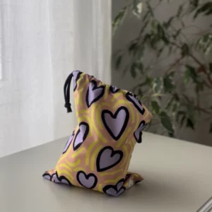 Pochette imperméable et écoresponsable, confectionnée à partir de chutes de tissus et fermée par des liens en coton recyclé, idéale pour transporter maillot mouillé, produits de beauté ou linge sale en voyage.