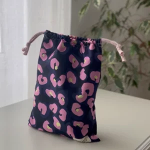Pochette imperméable et écoresponsable, confectionnée à partir de chutes de tissus et fermée par des liens en coton recyclé, idéale pour transporter maillot mouillé, produits de beauté ou linge sale en voyage.