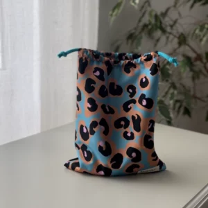 Pochette imperméable et écoresponsable, confectionnée à partir de chutes de tissus et fermée par des liens en coton recyclé, idéale pour transporter maillot mouillé, produits de beauté ou linge sale en voyage.